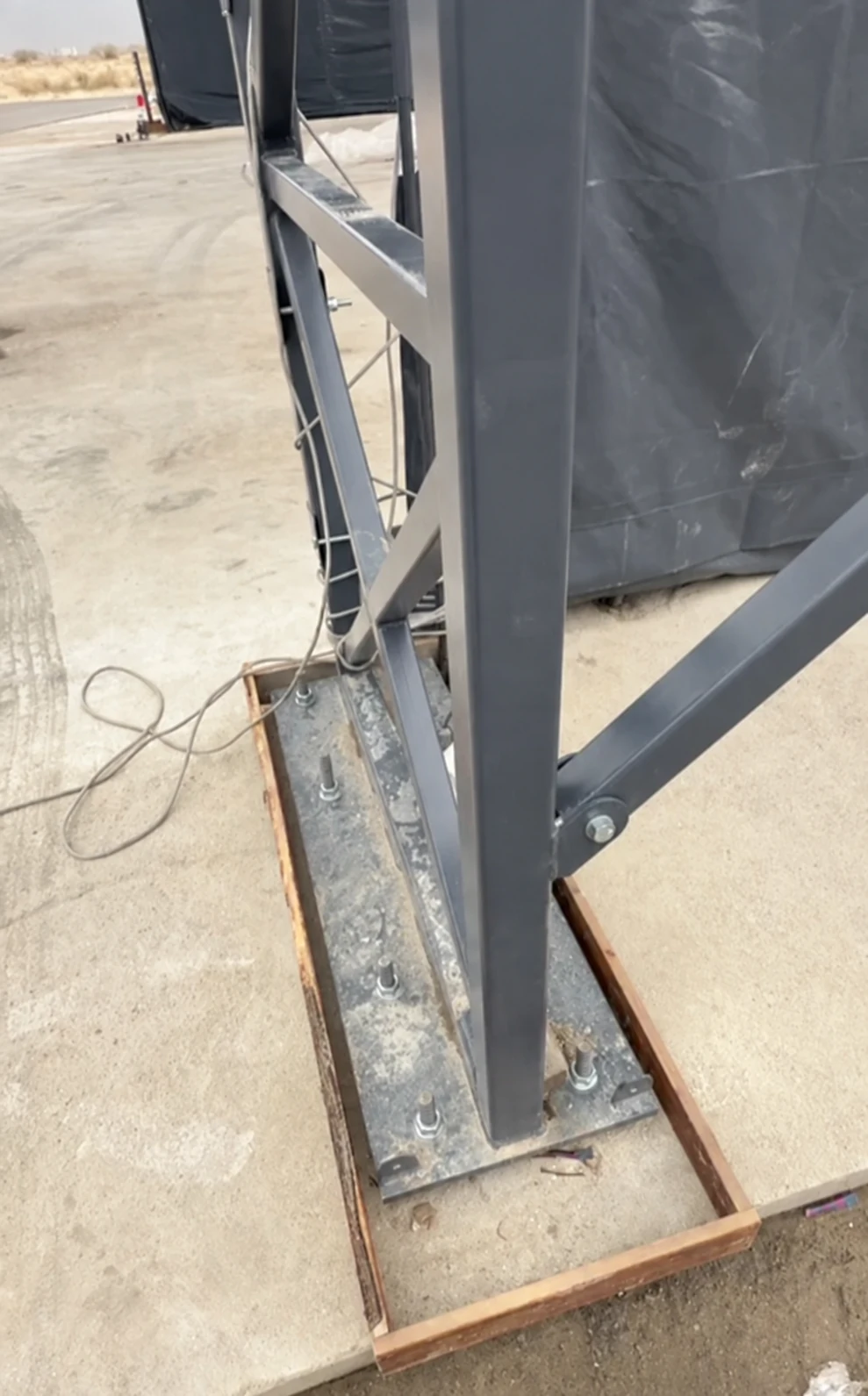 Editorial adaptation of a steel support base plate and visible anchor bolts on concrete.