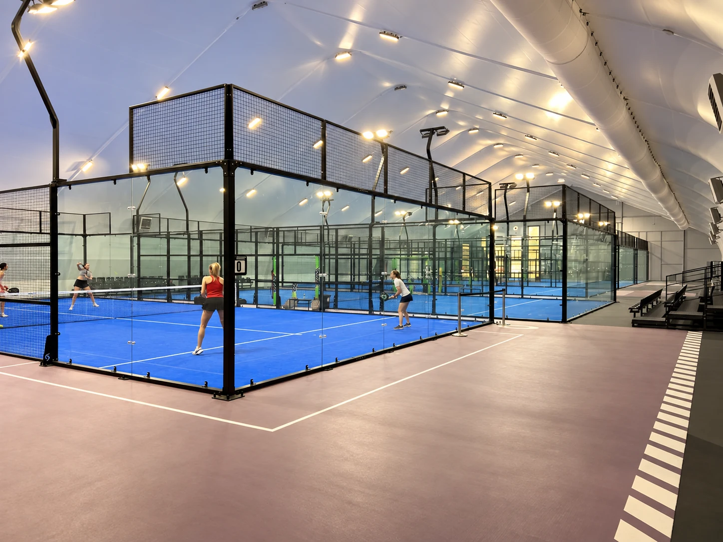 Editorial adaptation of a finished blue padel court inside a covered sports venue.