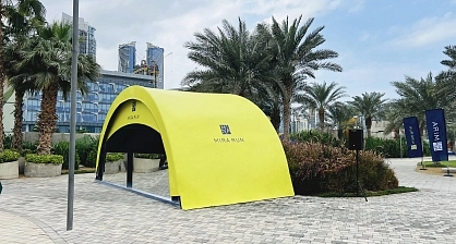 Bright yellow custom-branded Mira Run tent with blue interior entrance and high-visibility double-sided printing in Dubai urban plaza with skyscraper backdrop