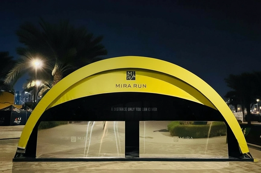 LED-illuminated modular arch event pavilion for Mira Run Dubai nighttime activation with strategic logo placement and wind-resistant structure amid palm trees
