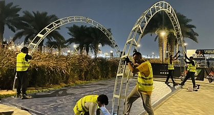 Metal arch framework assembly for event tent for Mira Run Dubai event with specialized flooring installation crew and waterfront venue setting at twilight