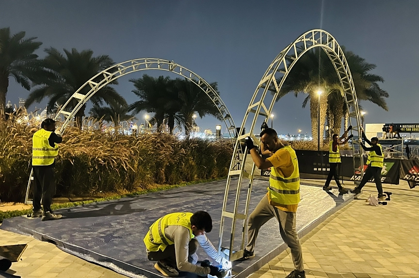 Metal arch framework assembly for event tent for Mira Run Dubai event with specialized flooring installation crew and waterfront venue setting at twilight